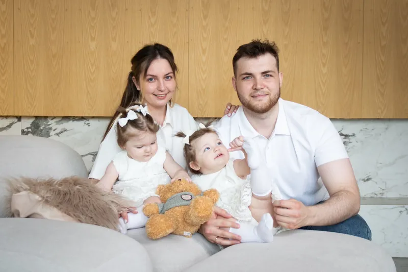 Родители с двумя детьми и игрушечным медведем на диване